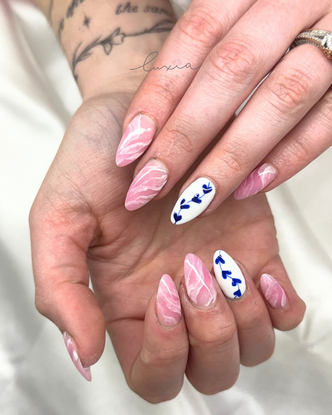 Pink marble nails with navy botanical leaf accent